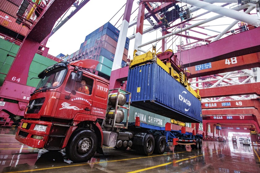 A worker waits to transport containers at the container port in Qingdao in eastern China's Shandong province on Tuesday, Jan. 14, 2020. China's exports rose 0.5% in 2019 despite a tariff war with Washington after growth rebounded in December on stronger demand from other markets. (Chinatopix Via AP)
