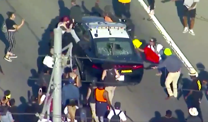 Numerosos manifestantes del movimiento Black Lives Matter (Las vidas de los negros importan) atacan a una patrulla de Caminos de California en el centro de Los Ángeles, en protesta por la muerte de un hombre negro en custodia de la policía de Minneapolis.