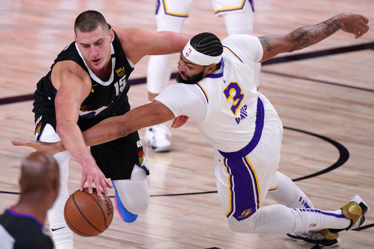 Nuggets center Nikola Jokic, left, and Lakers forward Anthony Davis battle for a loose ball.