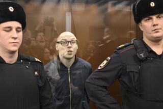 Russian poet Artyom Kamardin stands inside the defendants' glass cage during their verdict announcement at a court in Moscow