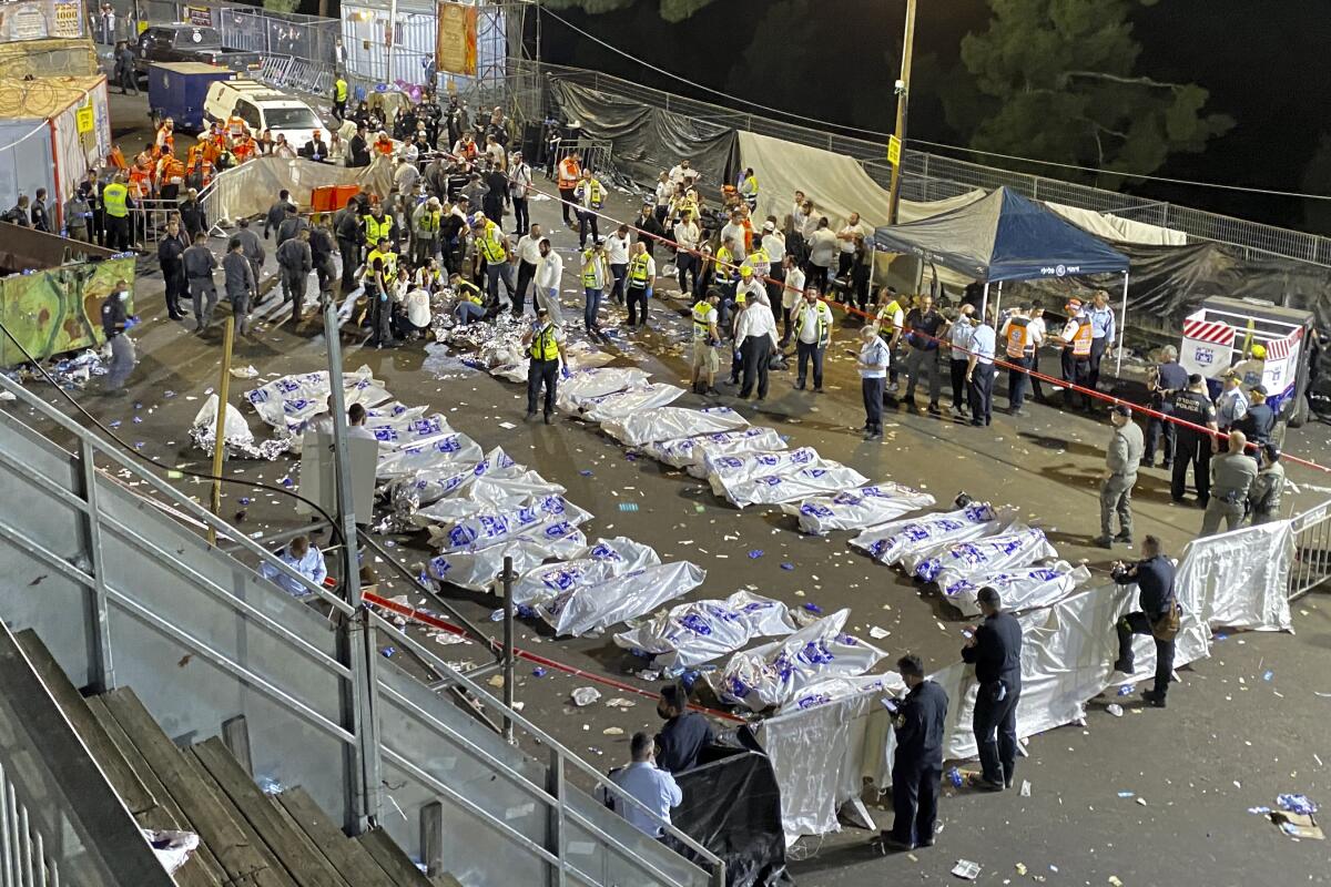 Israeli security officials and rescuers stand around the bodies of Lag Baomer victims.