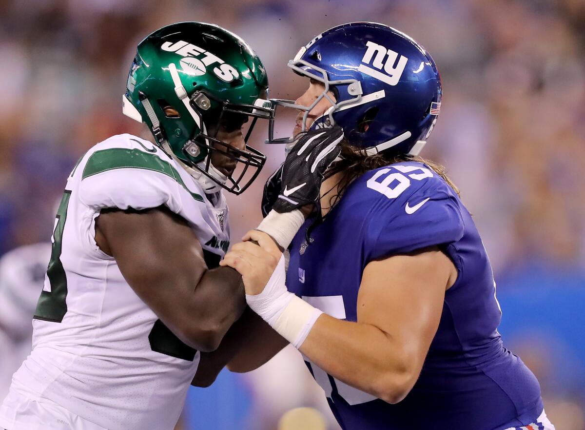New York Jets linebacker Tarell Basham, left, and New York Giants guard Nick Gates battle for position during a preseason game Aug. 8 at MetLife Stadium.