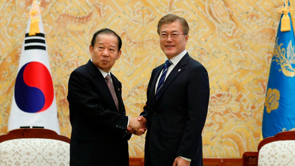 South Korean President Moon Jae-in shakes hands with Toshihiro Nikai, secretary general of the Japanese Liberal Democratic Party, during their meeting at the Presidential Blue House in Seoul on June 12.