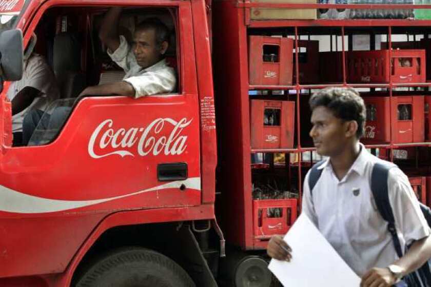 A man walks past a truck that distributes Coca Cola in Mumbai, India. The world's biggest beverage maker said Tuesday that it will invest an additional $3 billion in India through 2020.