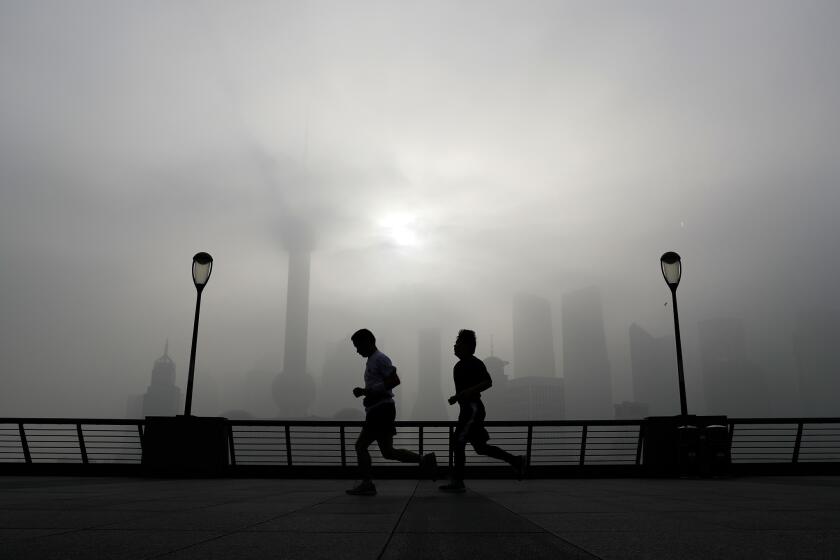 People jog past the Pudong Financial District shrouded with fog and pollution at the Shanghai Bund in Shanghai, China on April 14. On Friday, the U.S. and China are expected to join 160 other nations in signing the Paris global climate pact.