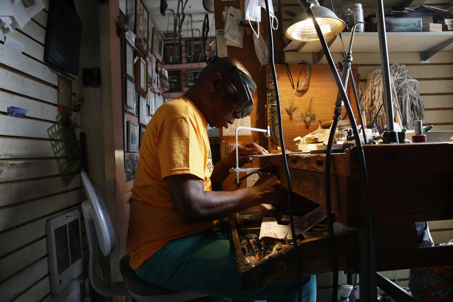 Earl Harley, 80, cuts metal into the shape of Africa. He makes buckles for the rich and famous from his tiny stall in Harlem, N.Y.