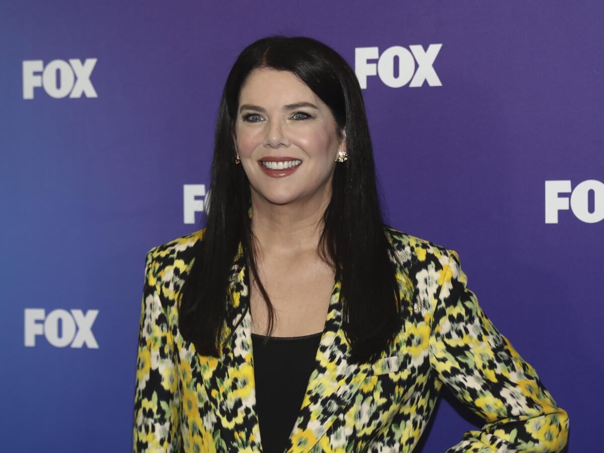 Actor Lauren Graham smiles in front of a purple wall with the word Fox repeated on it