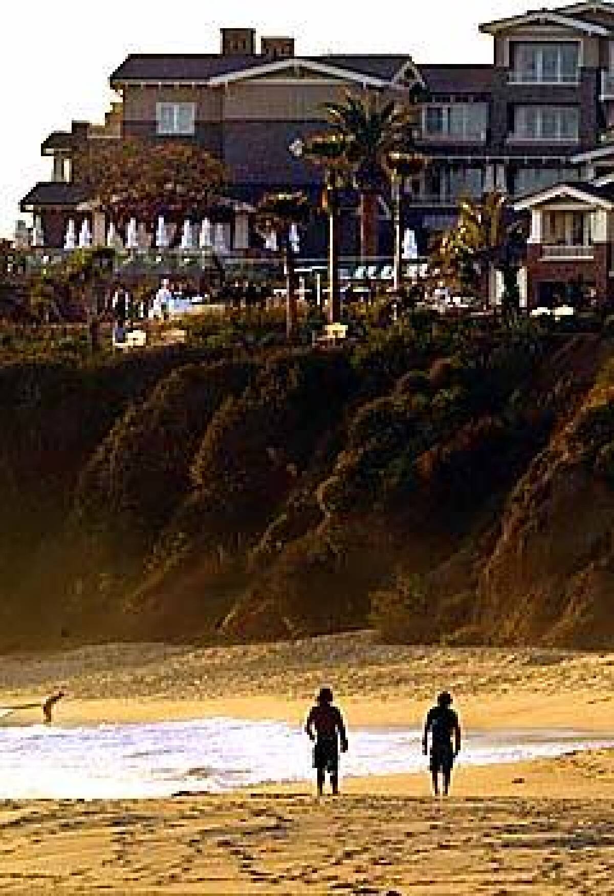 Surfers stroll below the new Montage Resort & Spa in Laguna Beach. The bluff was once home to a trailer park.