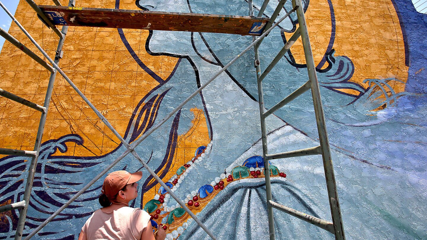 Rosa Lopez works on the details of a mural at Bradley Avenue and Van Nuys Boulevard.