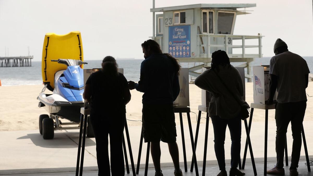 Voters cast ballots at the Venice Beach Lifeguard Operations Headquarters against a beach backdrop.