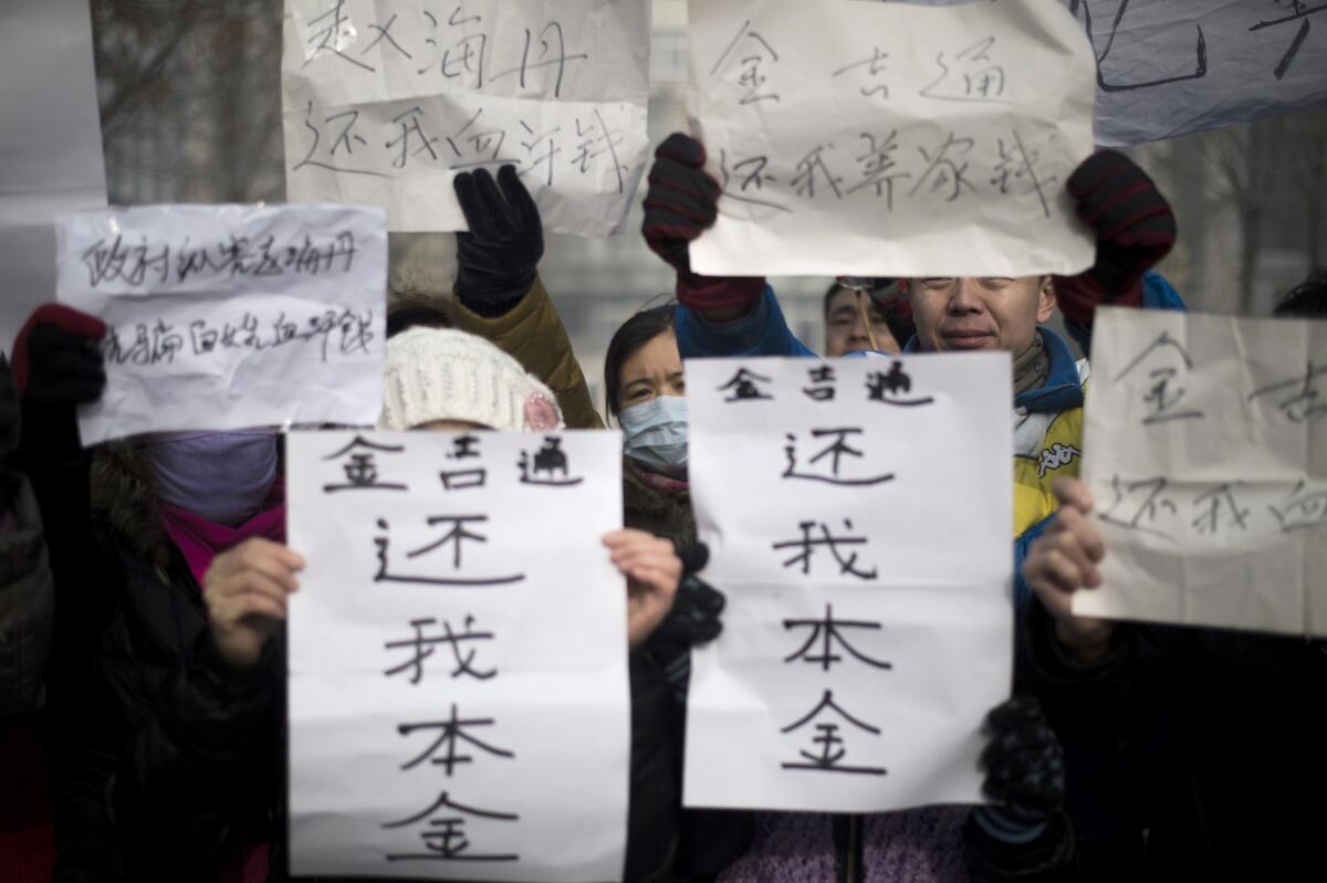 People hold up signs reading "we are not paid" on Dec. 10 as a group protests alleged local government wrongdoing and unpaid wages outside courthouse where a former deputy director of China's top economic planning agency, was convicted of bribery and sentenced to life in prison.