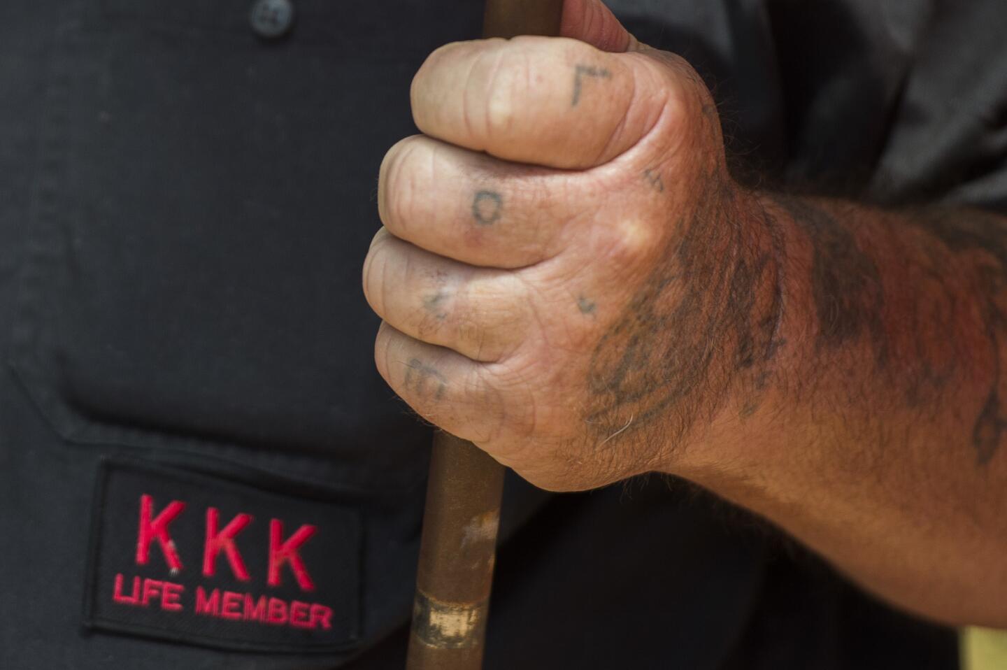 A member of the Ku Klux Klan, with the word "Love" tattooed on his fingers, holds a flag during a rally, calling for the protection of Southern Confederate monuments, in Charlottesville, Virginia on July 8, 2017.