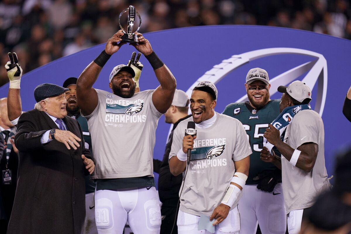Philadelphia defans oyuncusu Fletcher Cox, Jalen Hurts ve Terry Bradshaw'ın yanında George Halas Kupasını kaldırıyor.