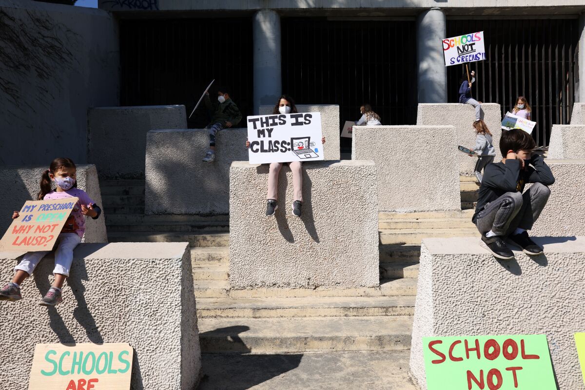 Students hold protest signs during a rally at Pan Pacific Park.