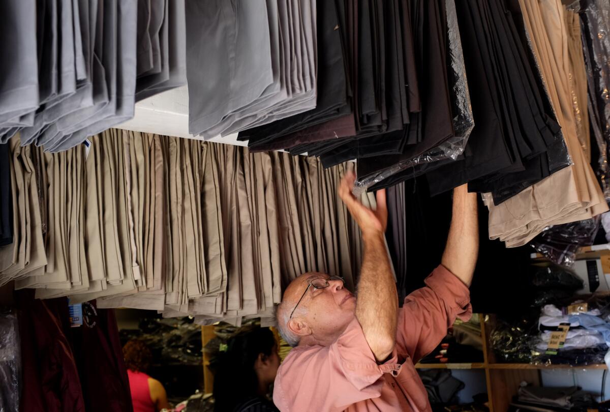 Sigifredo Lopez, who has a business selling school and soccer uniforms in the San Fernando Valley, looks through inventory at his small shop in August.