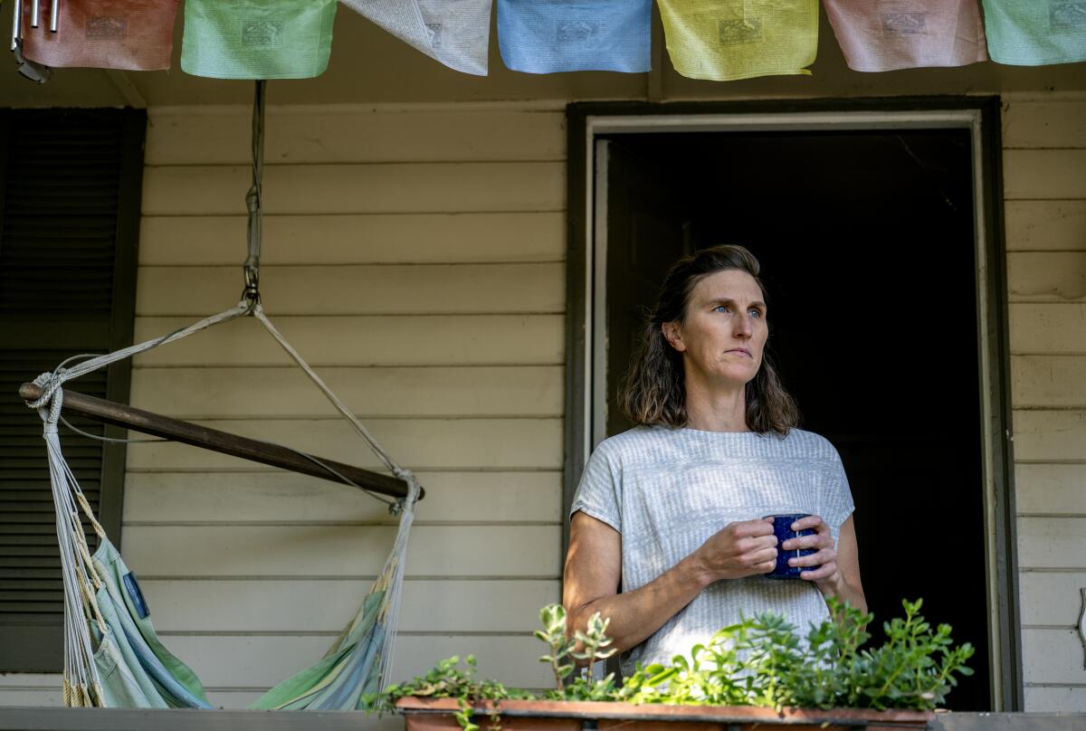 Former Caltrans executive Jeanie Ward-Waller stares out a widow holding a cup in her hands.