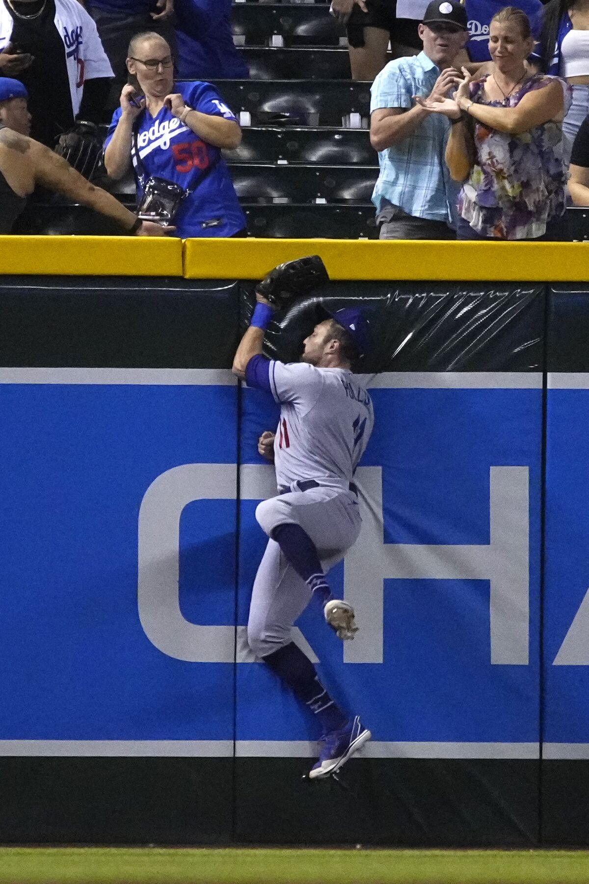 Dodgers left fielder AJ Pollock collides into the left-field wall as he catches a fly ball.