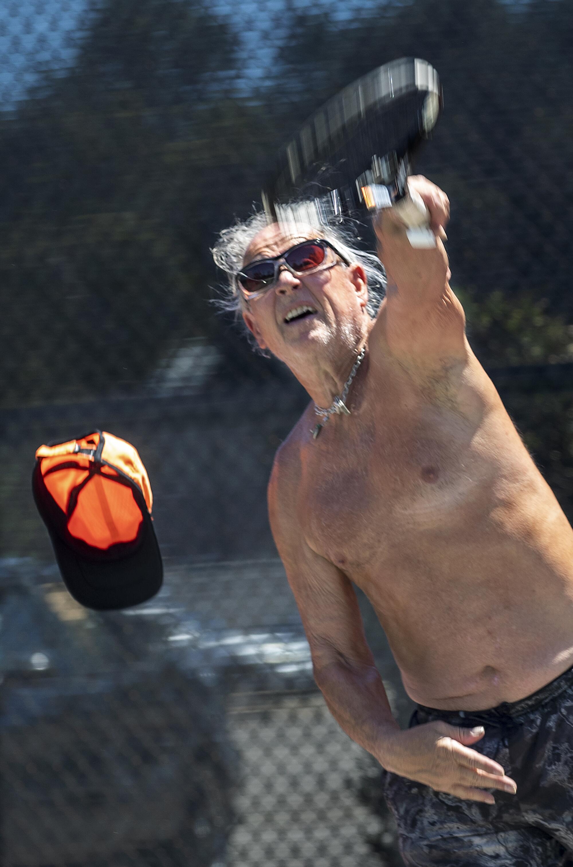 Michael Berns, 77, loses his hat while practicing his serve on a tennis court in Sherman Oaks on a hot Monday afternoon.