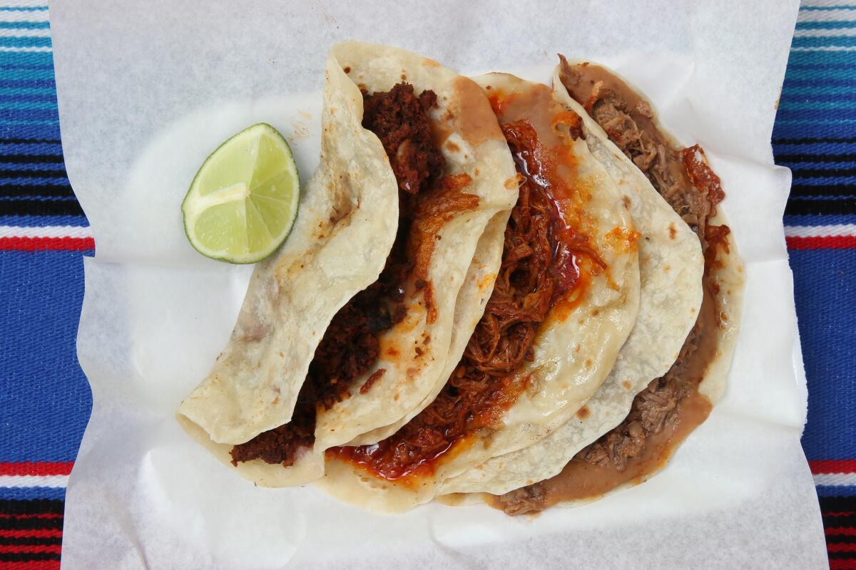 A plate of three tacos served with a lime wedge