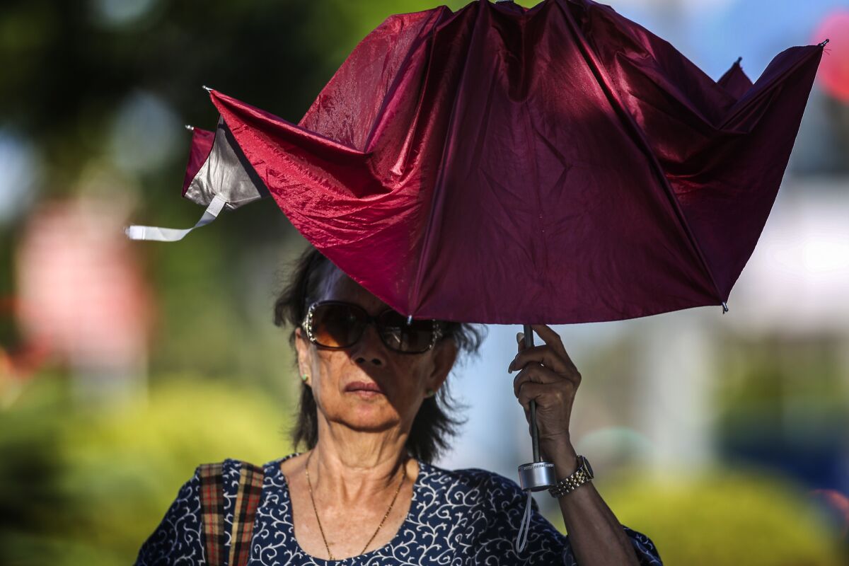 A woman uses a broken umbrella to shield herself from the sun in Los Angeles earlier this year.