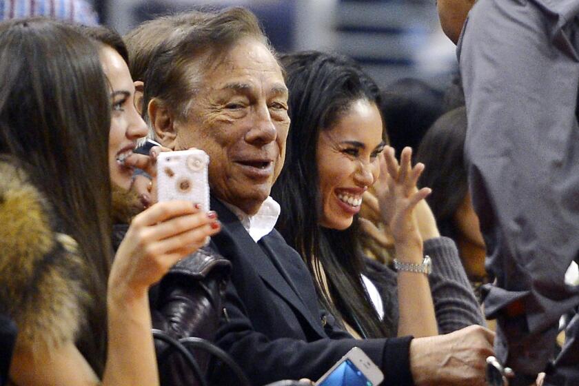 Los Angeles Clippers owner Donald Sterling, center, and V. Stiviano, right, watch the Clippers play the Sacramento Kings at Staples Center.