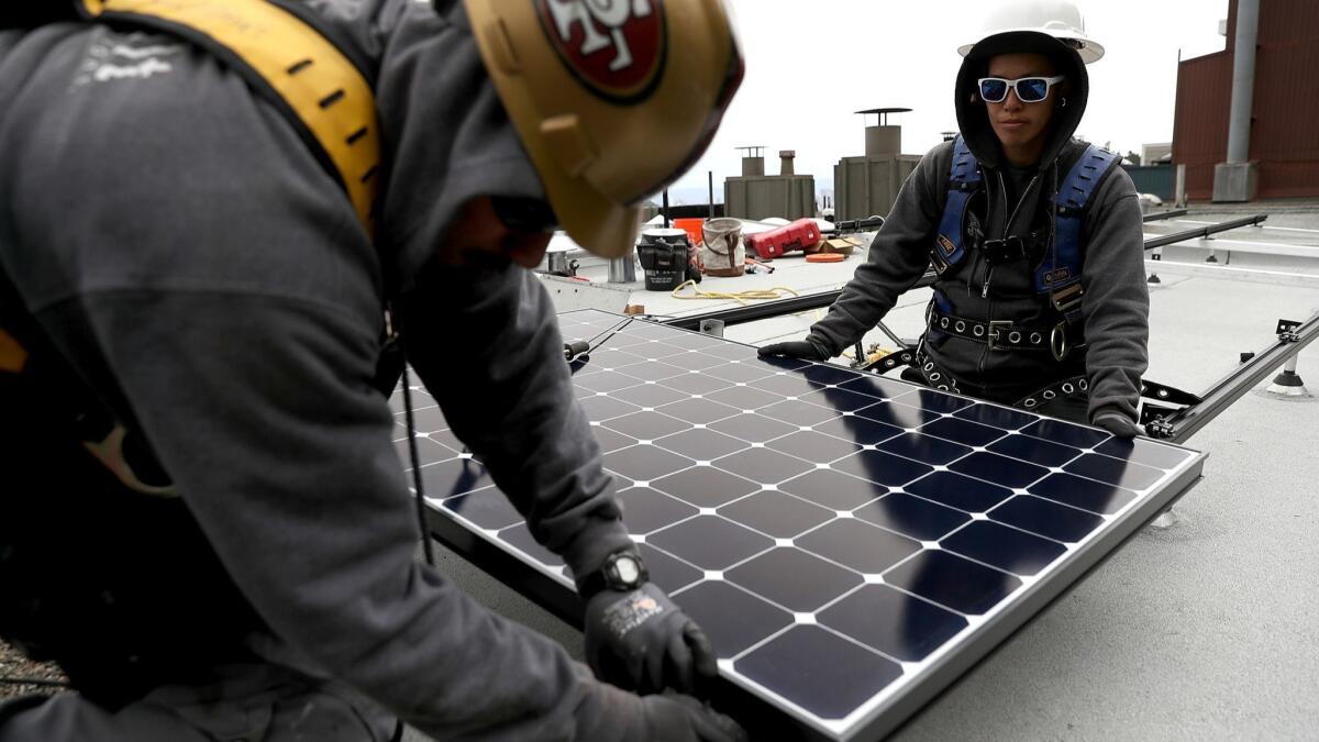Workers install a solar system on the roof of a home in San Francisco on May 9, 2018.