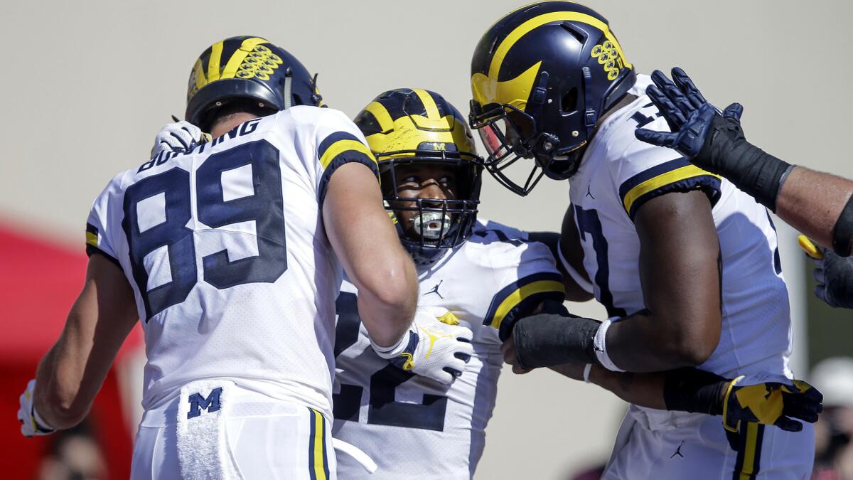 Michigan running back Karan Higdon, center, celebrates a touchdown with teammates Ian Bunting, left, and Tyrone Wheatley during the second half of an NCAA college football game against Indiana in Bloomington, Ind., Saturday, Oct. 14, 2017. Michigan won 27-20 in overtime.