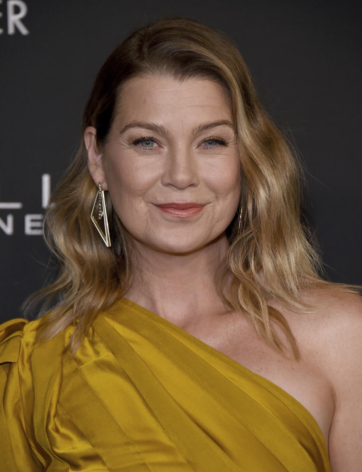 A woman smiles in a mustard-yellow gown.