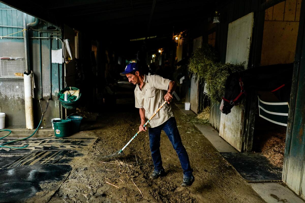 A backstretch worker cleans stables run by trainer Hector Palma at Santa Anita Park.