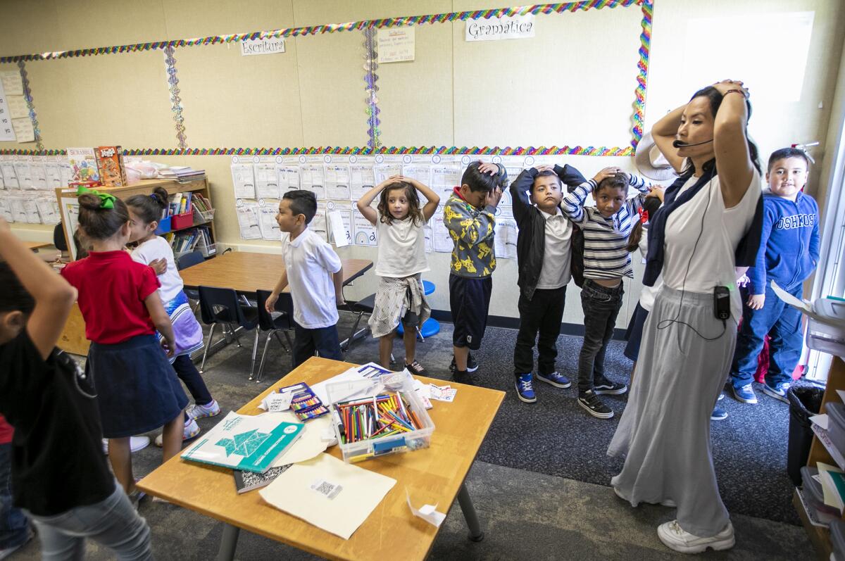 First-grade teacher Dulce Pena Wing instructs students to cover their heads.