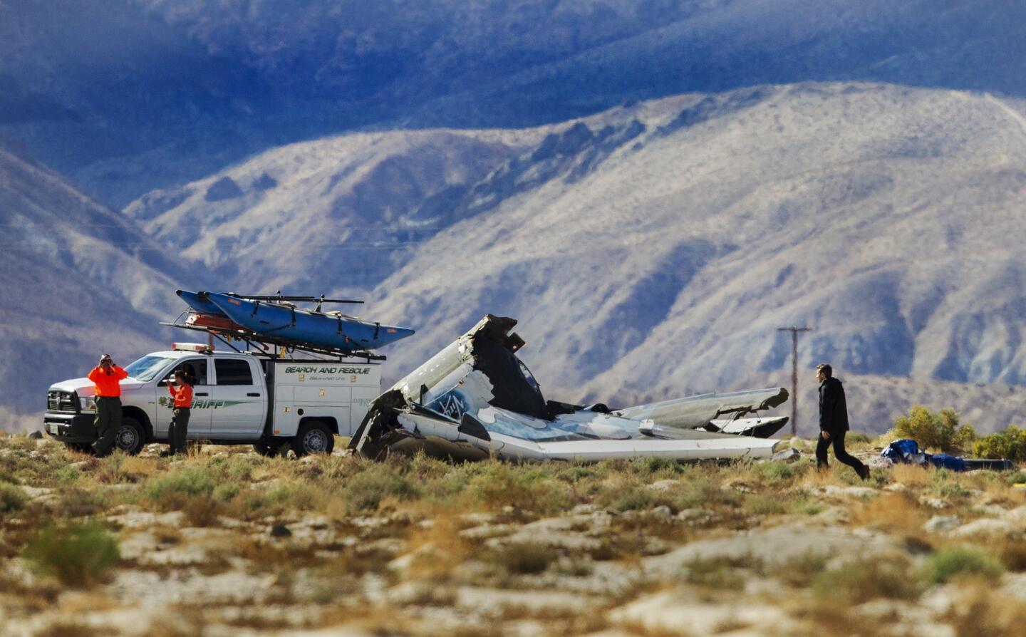 Kern County Sheriff officers keep watch as an investigator looks over the wreckage site of the Virgin Galactic SpaceShipTwo in Mojave.