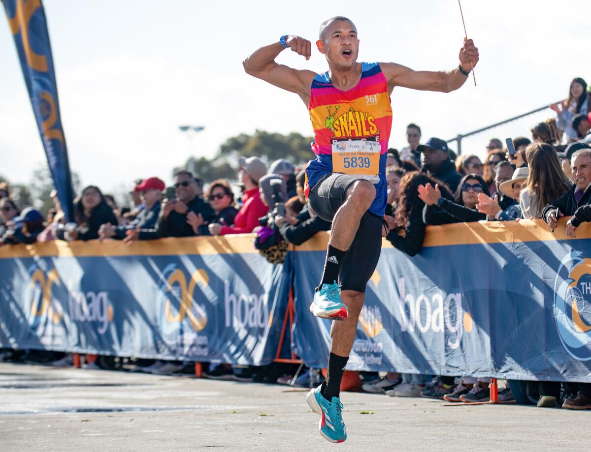 A runner shouts and jumps through the finish line of the Orange County Marathon and Half Marathon.