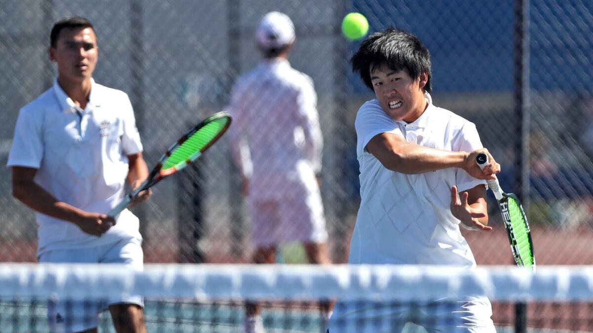 Fountain Valley High's Tommy Trinh, right, returns the ball for Fountain Valley High as doubles partner Justin Pham looks on during Wednesday's CIF Southern Section Division 2 semifinal match against JSerra.