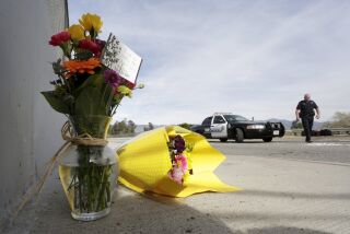 A San Bernardino police officer stands near flowers left near the scene of Wedneday's shooting rampage, at the Inland Regional Center, in San Bernardino.
