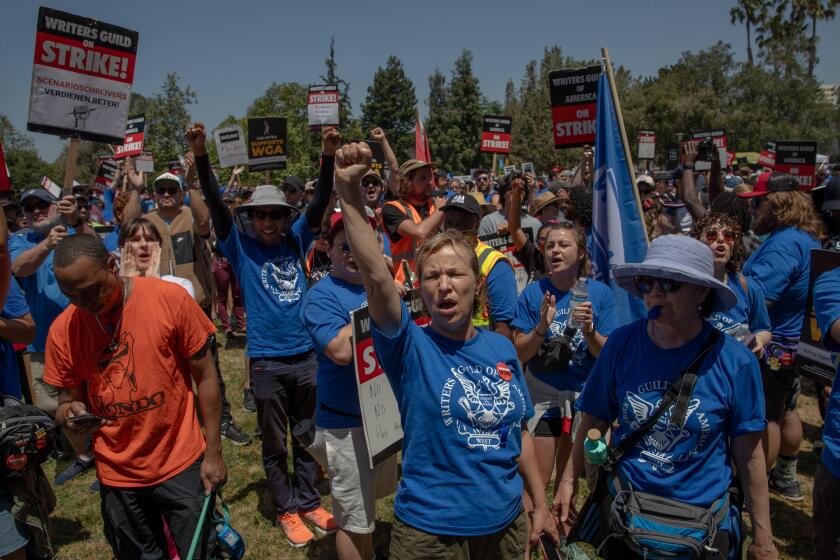 LOS ANGELES, CA - JUNE 21: A film writer Laura Harrington, center fist in air, and striking members of the Writers Guild of America and supporters rally at La Brea Tar Pits, Los Angeles, CA. (Irfan Khan / Los Angeles Times)