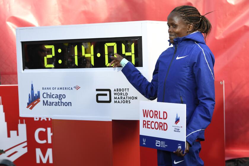 Brigid Kosgei of Kenya, poses with her time after breaking the world record with a time of 2:14:04 during the Chicago Marathon Sunday, Oct. 13, 2019, in Chicago. (AP Photo/Paul Beaty)