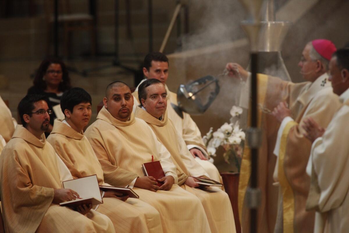 L.A. Archbishop Jose Gomez blesses the altar as new priests Fathers Juan Ochoa, left, Andrew Chung, Christopher Felix and John Palmer look on.