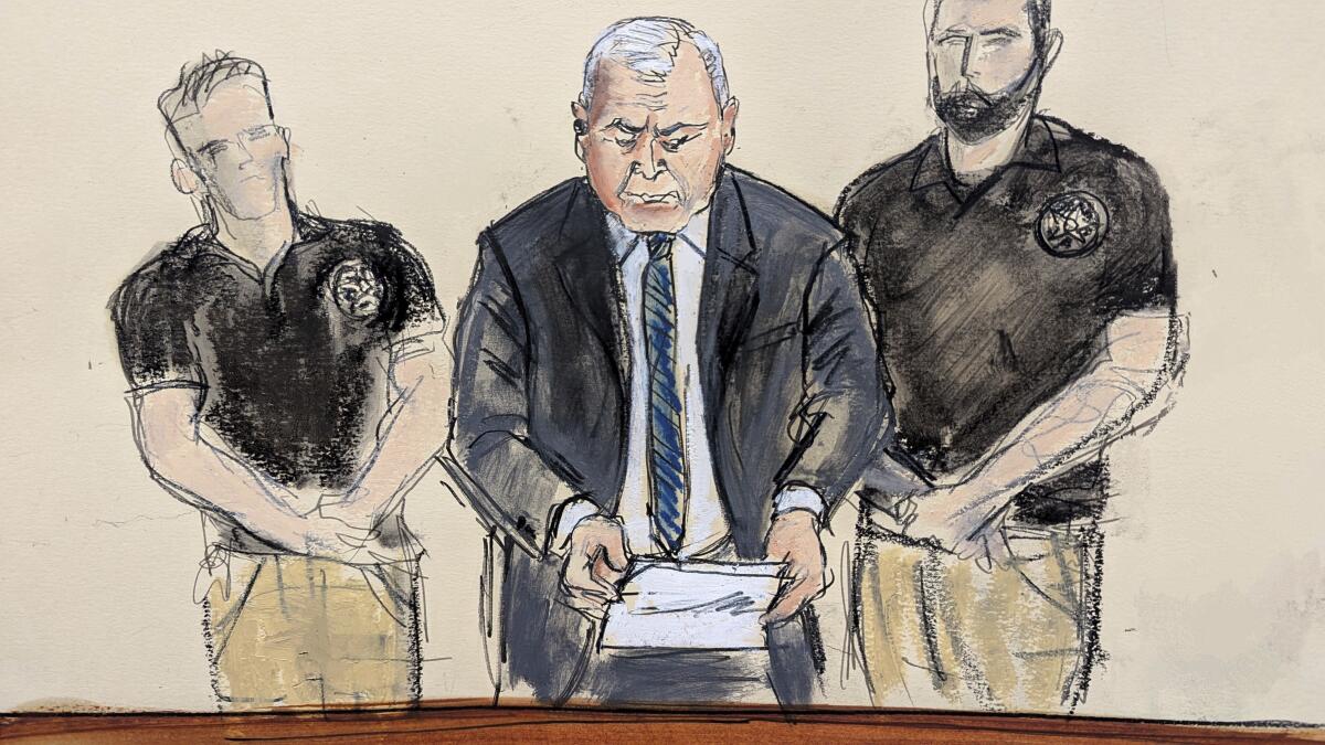 A court drawing of a man reading from a paper in a business suit with U.S. Marshals on either side