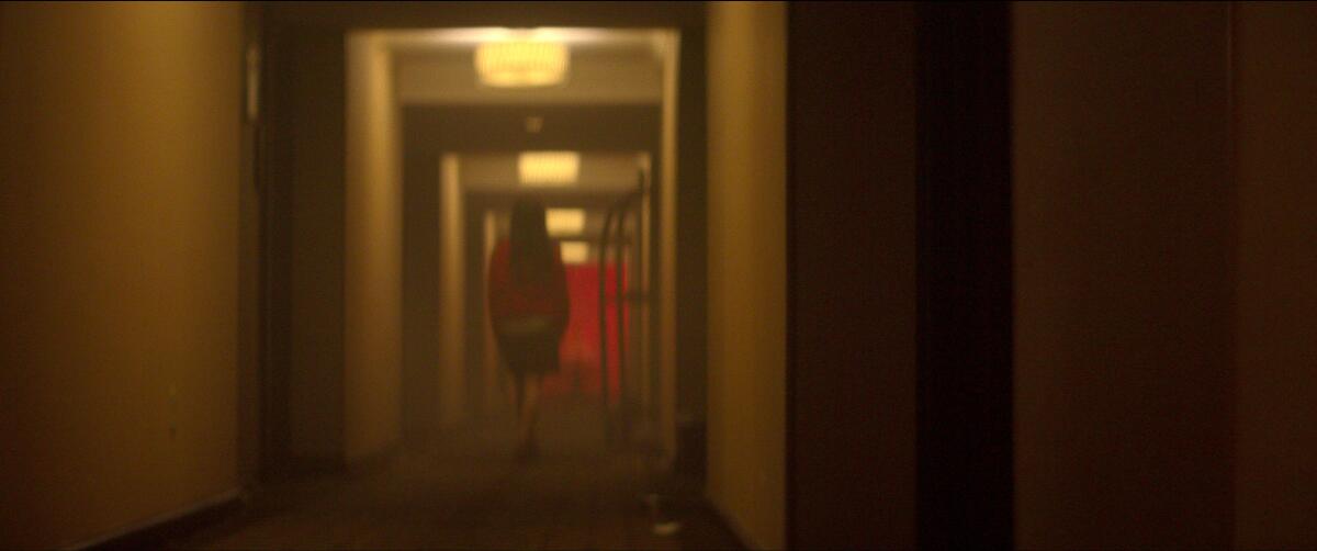 A woman walks down an empty hallway.