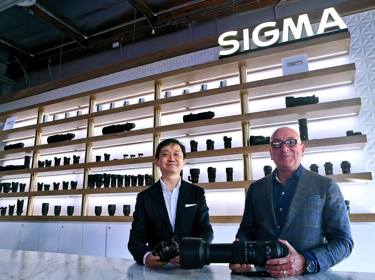 Sigma Corporation’s new business division manager and mechanics design engineer Yasuhiro Ohsone, left, and Sigma Corporation of America president Mark Amir-Hamzeh, right, with a wall full of lenses the company offers for still and cinema cameras, during grand opening celebration at the new location in Burbank on Saturday, Nov. 3, 2018. Sigma Burbank is the West Coast service, distribution and resource center for professionals and non-pro consumers.