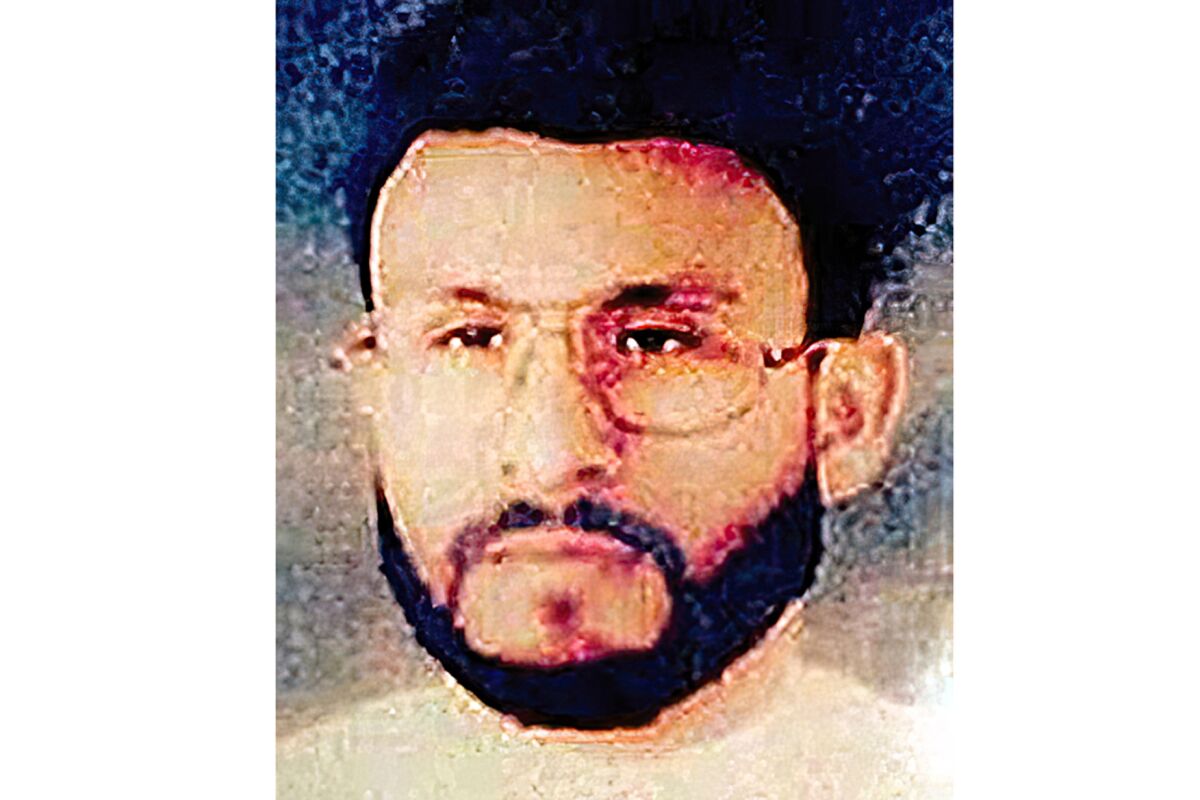 A grainy photo of a bearded man with glasses