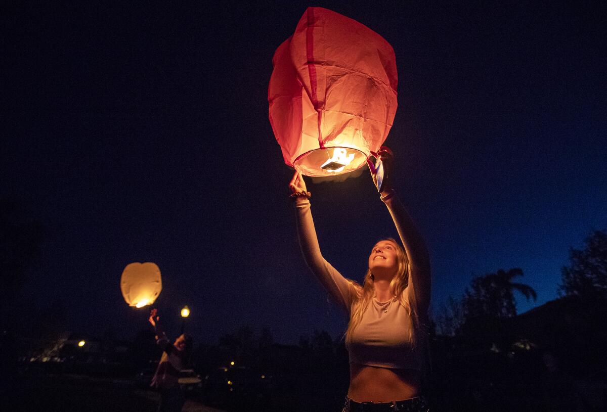 Claire Robbins prepares to launch a paper lantern during a surprise 16th-birthday celebration for her friend Madison Moore on Tuesday night in Huntington Beach.