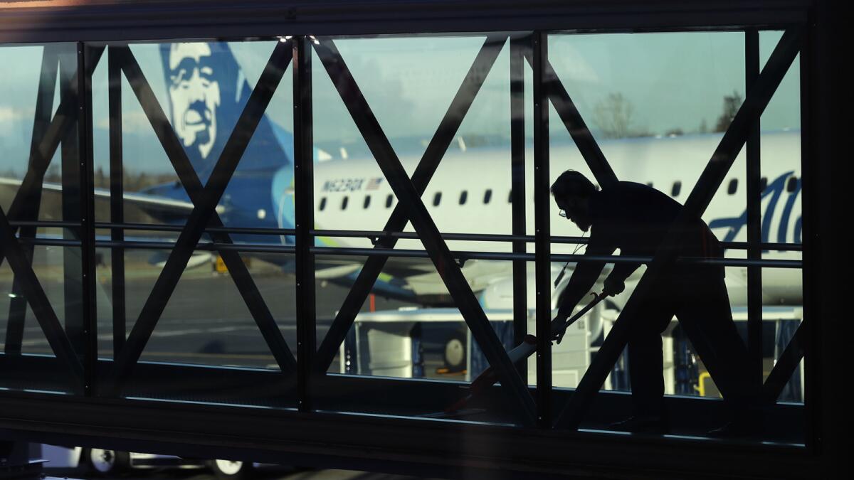 A worker cleans a jet bridge before passengers board a flight in Everett, Wash.