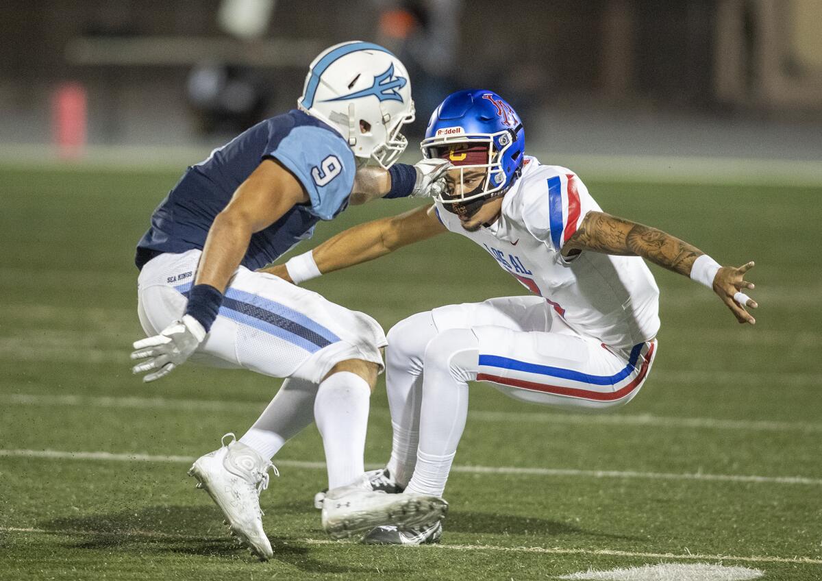Corona del Mar's Christian Brooks grabs the face mask of Los Alamitos' Malachi Nelson during a Sunset League game.