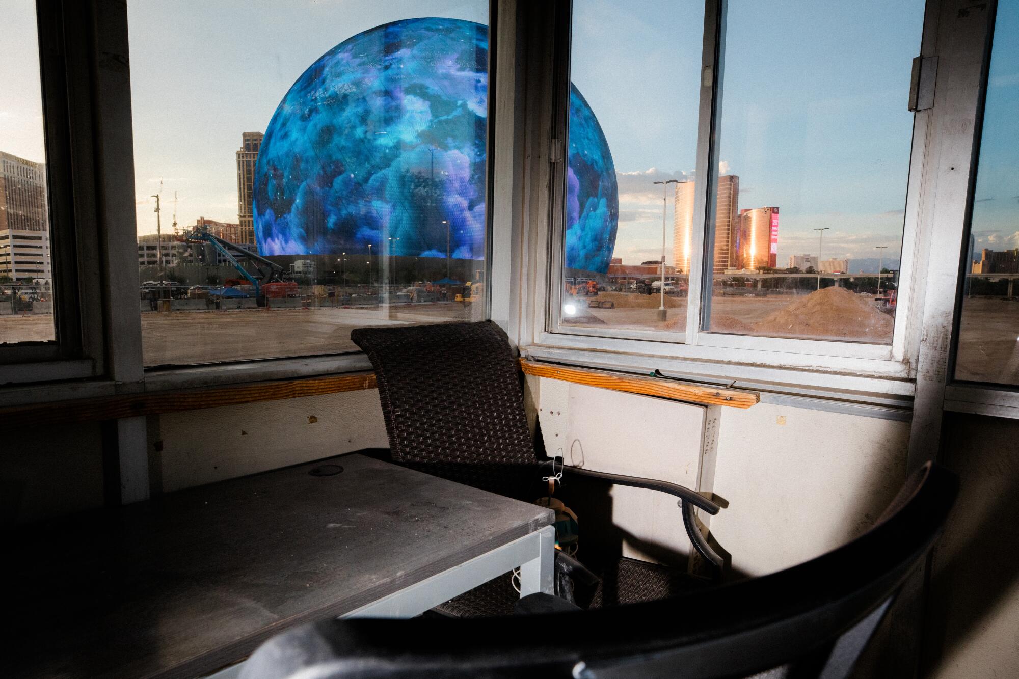 A spherical building whose surface features a bubbling blue cosmic pattern is seen through a security booth.