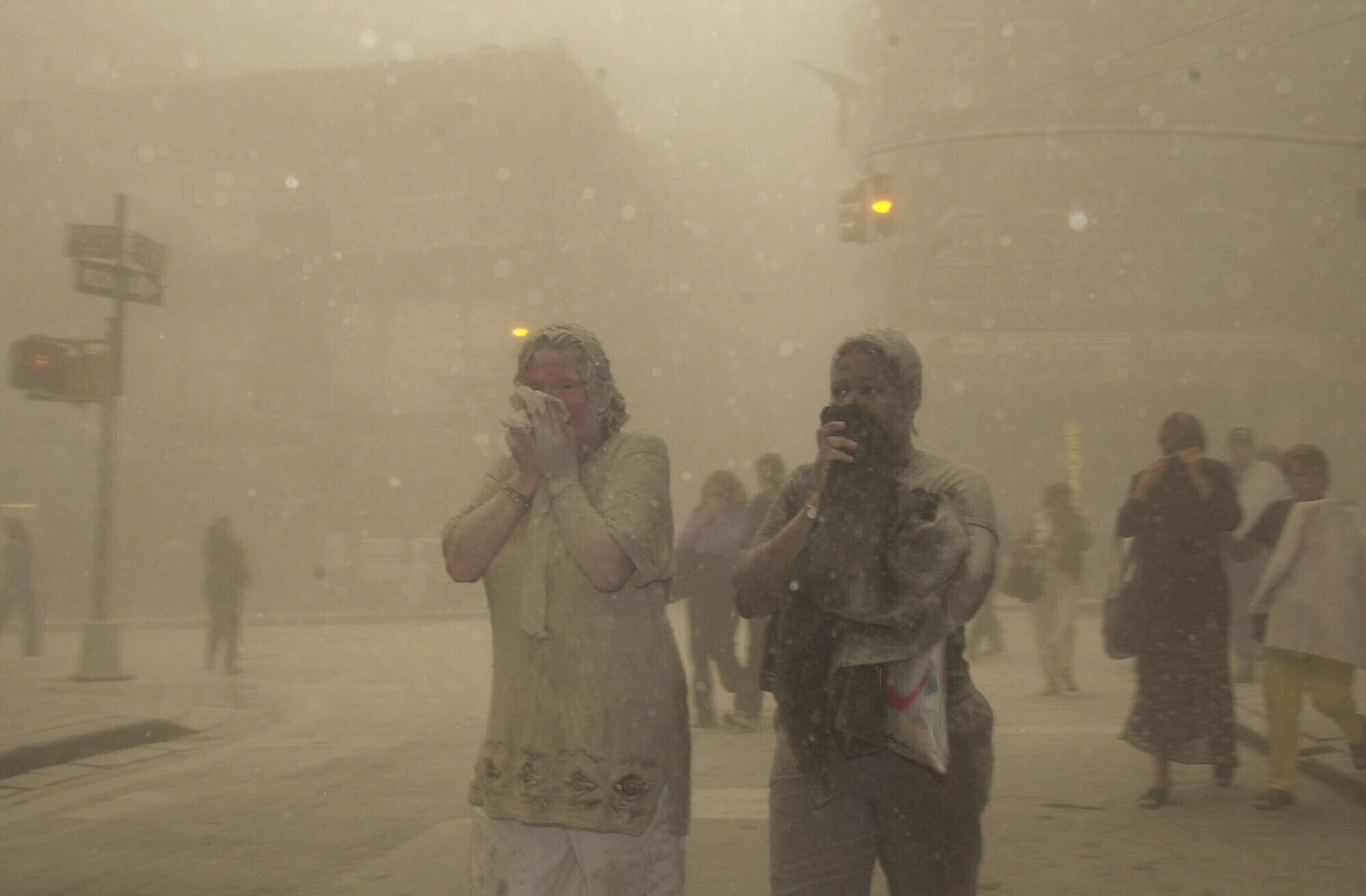 People shrouded by smoky air cover their mouths as they walk in the street