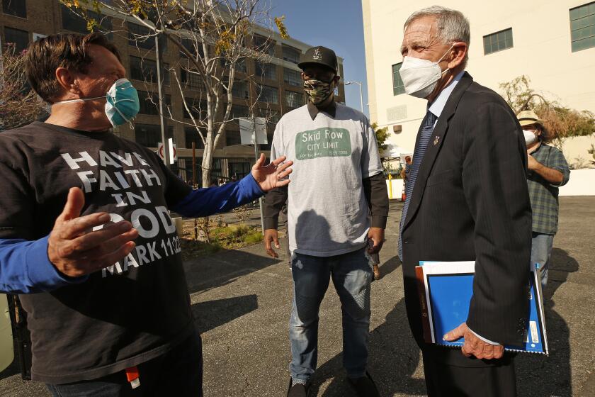 LOS ANGELES, CA - FEBRUARY 04: Pastor Donald Dermit, left, and General Jeff, middle, spokesperson for the Skid Row Advisory Council talk with U.S. District Judge David Carter following an urgent meeting the Judge called under a tent in the parking lot of the Downtown Women's Center on Skid Row Thursday to discuss worsening conditions and what the U.S. District Judge David Carter considers the city's failure to respond to the recent rainstorm that threatened lives on downtown streets. Combined with the COVID-19 pandemic and soaring mental health and substance abuse issues, homelessness in the region is comparable to "a significant natural disaster in Southern California with no end in sight," U.S. District Judge David Carter wrote in an order filed late Sunday in federal court. Skid Row on Thursday, Feb. 4, 2021 in Los Angeles, CA. (Al Seib / Los Angeles Times).