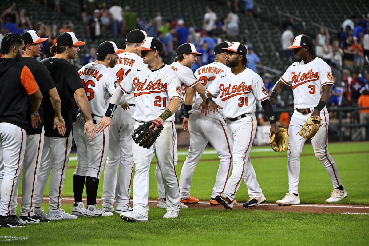 Baltimore Orioles players greet each other after defeating the Toronto Blue Jays 6-5 in a baseball game, Tuesday, Aug 9, 2022, in Baltimore. (AP Photo/Terrance Williams)