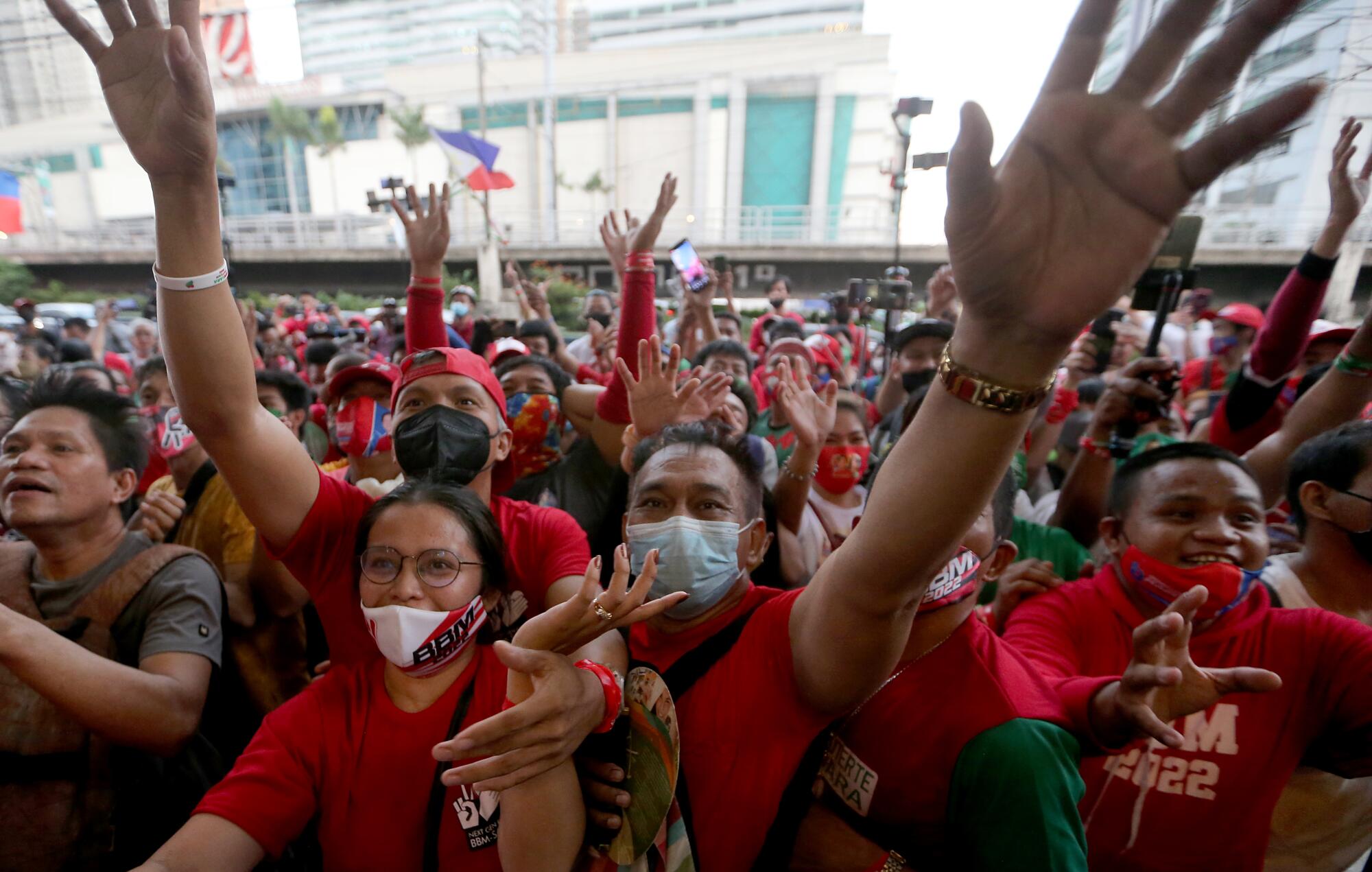 Supporters of presidential candidate Bong Bong Marcos celebrate with hands raised.