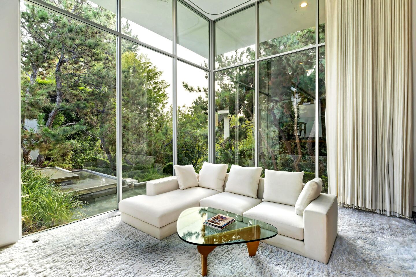 This custom Midcentury revolves around indoor-outdoor living with a series of rooms surrounding a courtyard and a bridge over the swimming pool that runs from the owner's suite to the living room.